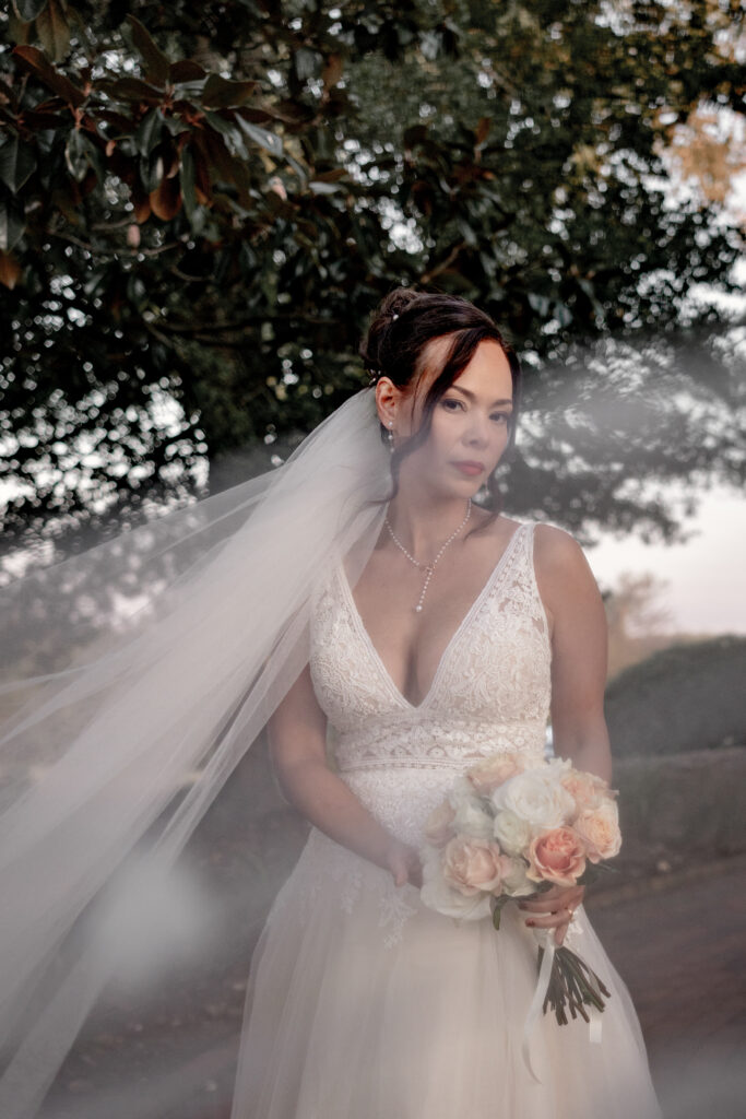 Bride looking at camera while veil flies in front of camera.