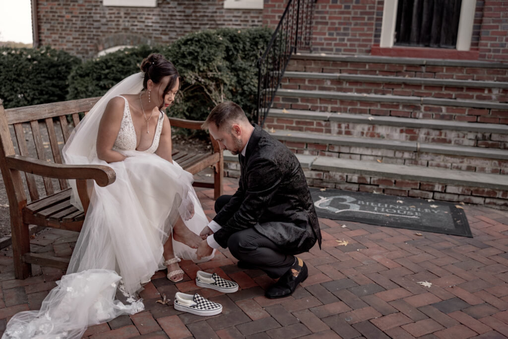 Bride and groom changing shoes before going to reception at a bench.