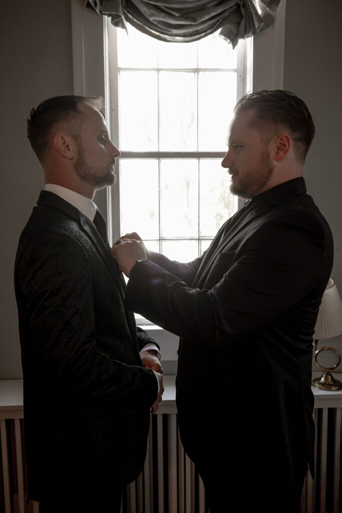 groom getting his tie adjusted by his groomsmen.