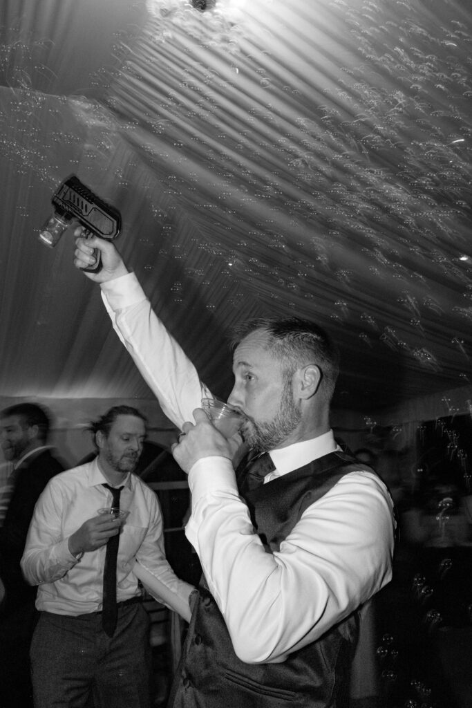 Groom drinking and using bubble gun.