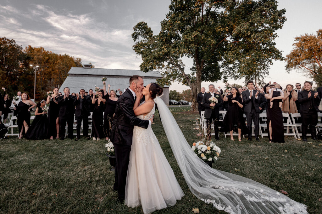 couple having their first kiss as a married couple in front of their friends and family attending their ceremony.