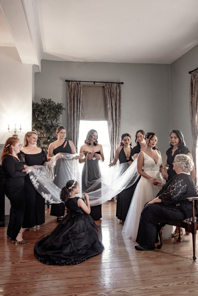 bride with 9 bridesmaid helping her put on veil. 