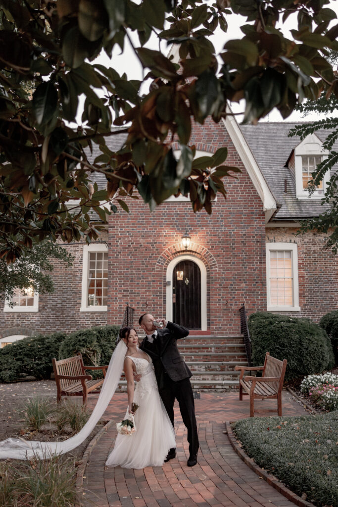 bride and groom standing in front of billingsley manor doing a dip.