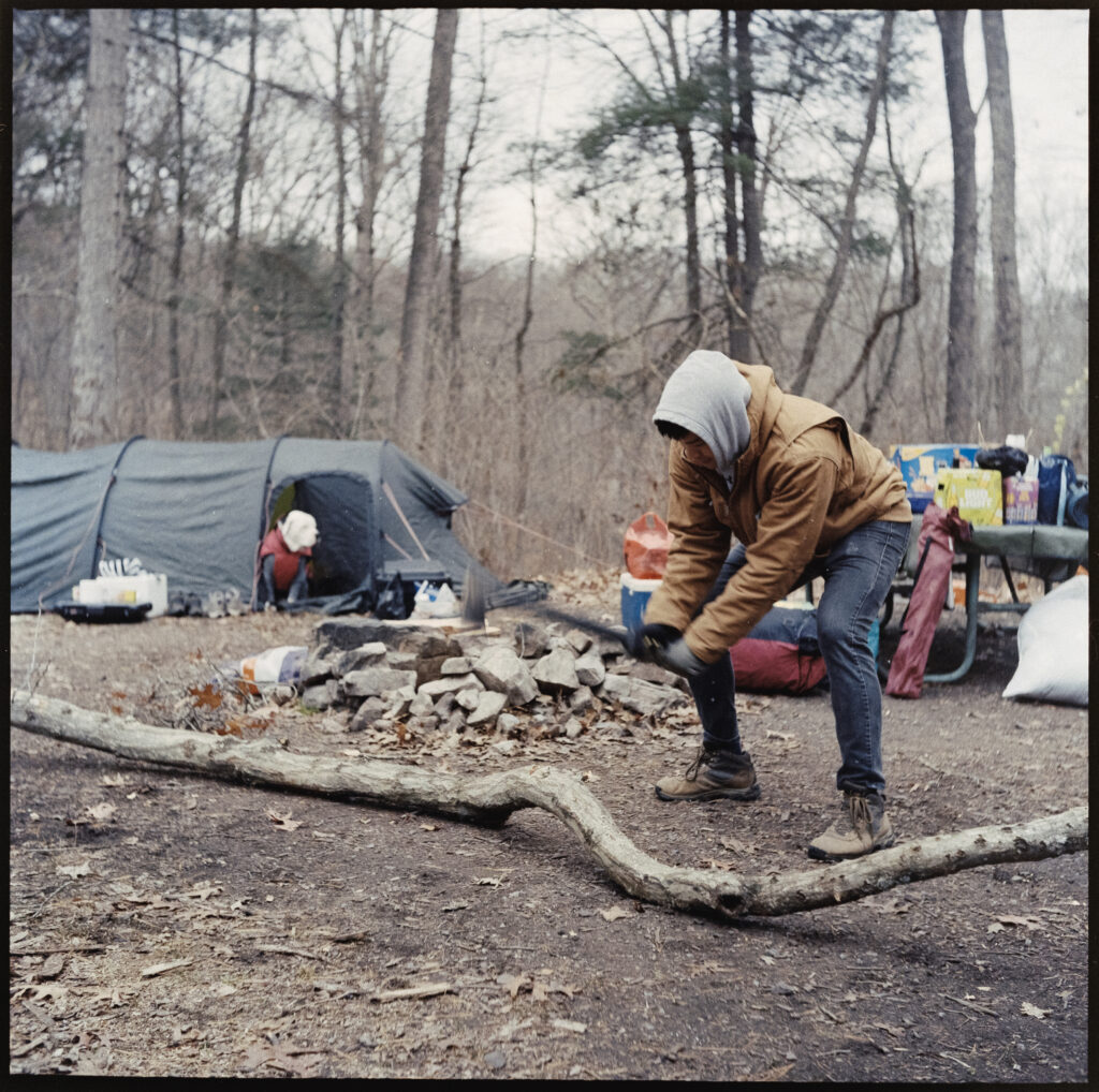 Man chopping wood on campsite.