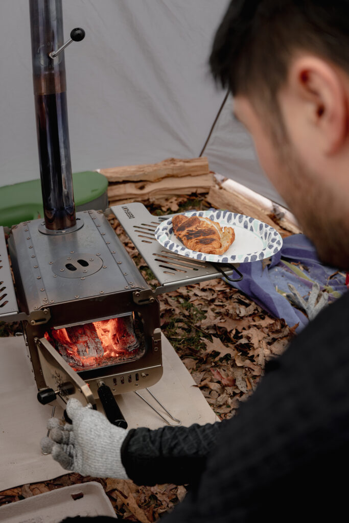 Man checking on firewood inside hot tent.